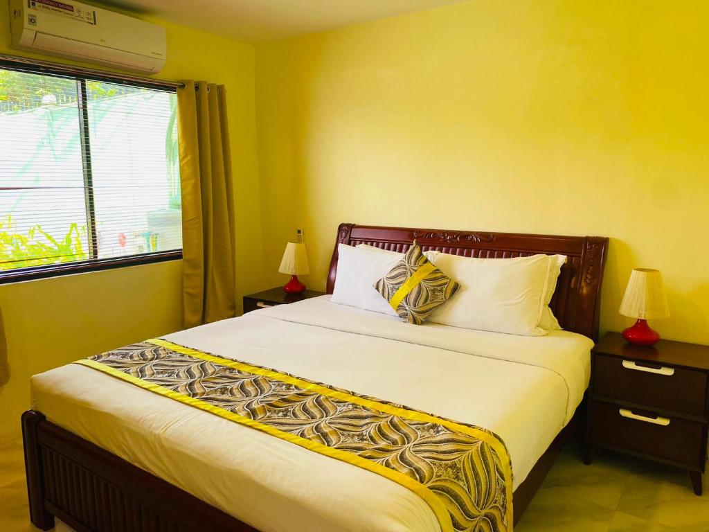 Un dormitorio con una cama grande con paredes amarillas y una ventana en Mariegold Villa Resort, en Suba