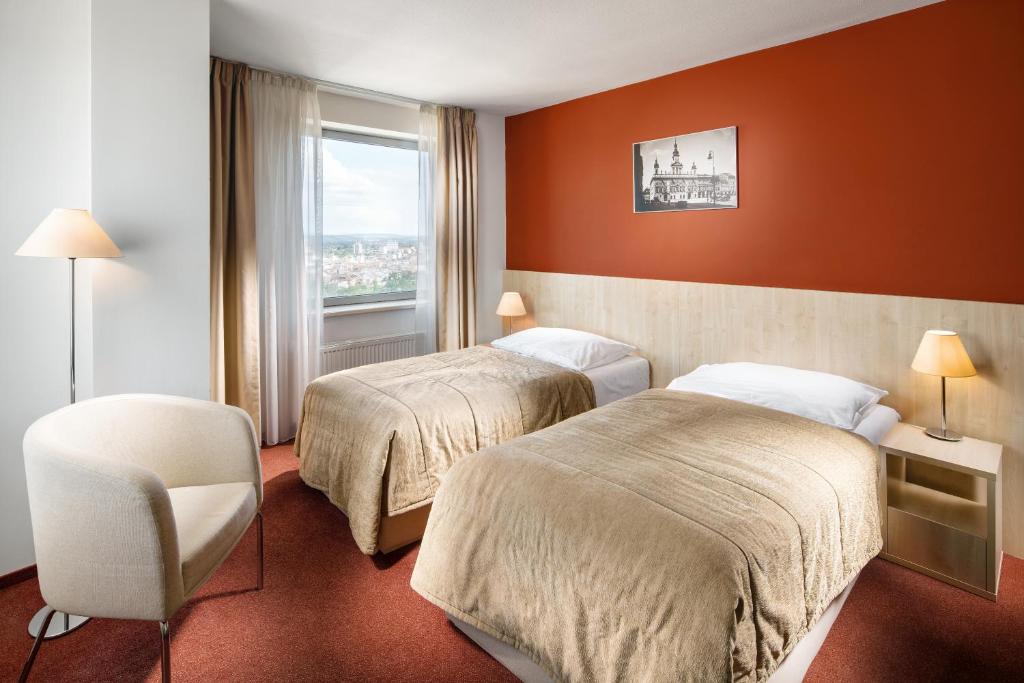 a hotel room with two beds and a chair at Clarion Congress Hotel České Budějovice in České Budějovice