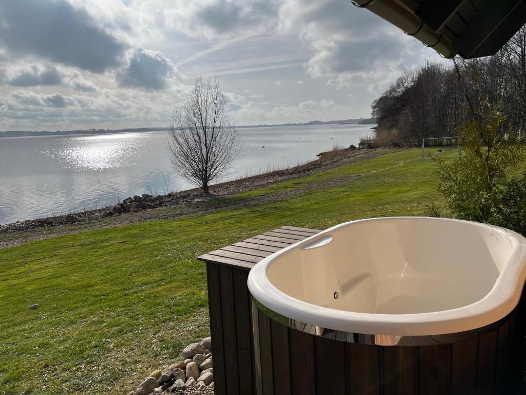 une baignoire assise sur l'herbe à côté d'une masse d'eau dans l'établissement Cottage with Seaview, à Holbæk