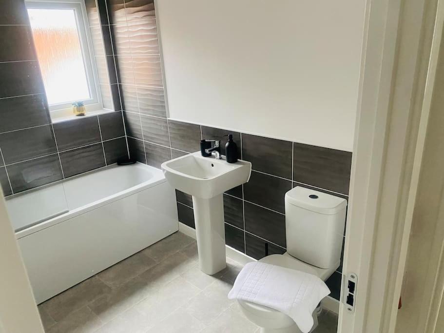 a bathroom with a sink and a toilet and a bath tub at Brand New 3 Bedrooms Detached House in Westhoughton