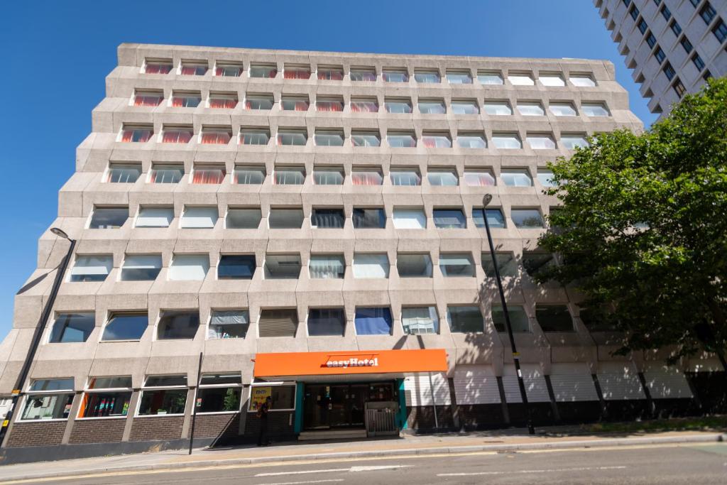 un palazzo alto con un cartello arancione davanti di easyHotel Croydon a Croydon