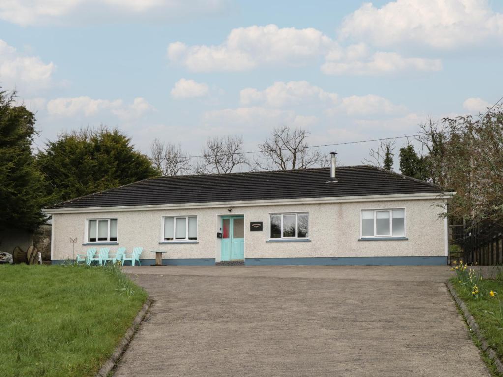 a white house with a blue door and two chairs at Sheemore View in Kilclare