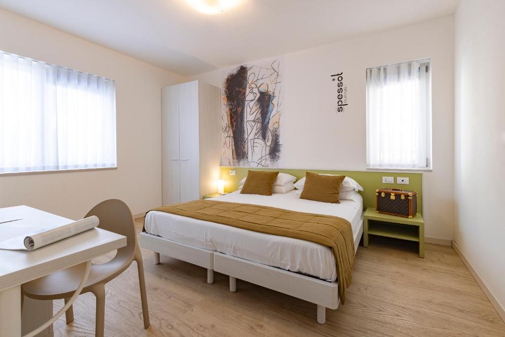 um quarto com uma cama, uma secretária e janelas em Art Hotel Principe em Lignano Sabbiadoro