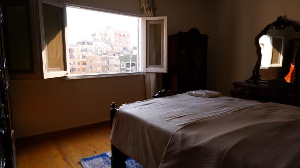 a bedroom with a bed and a large window at غرفة هادئه بمنزل قريب من المطار 701 in Cairo