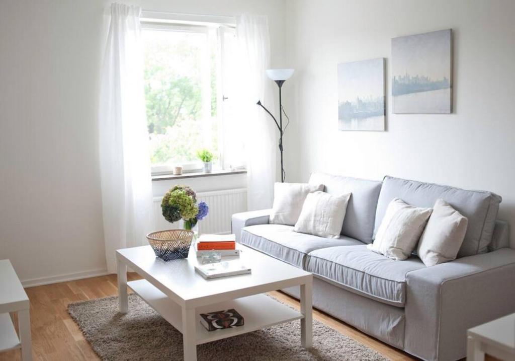a white living room with a couch and a table at Lovely 1 bedroom flat in Larsberg, Lidingo in Kottla
