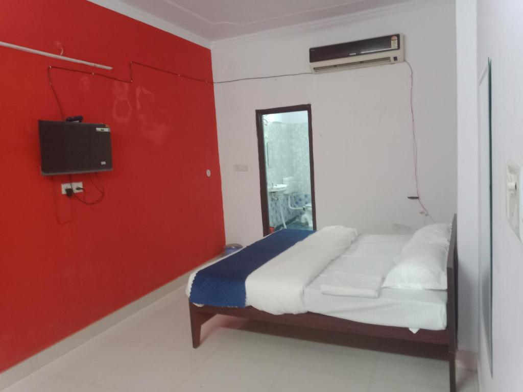 1 dormitorio con cama y pared roja en Hotel Rudra Palace, en Lucknow