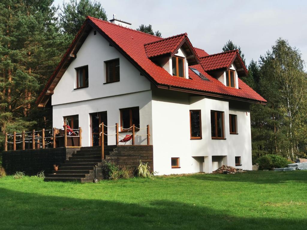 een groot wit huis met een rood dak bij Dom w lesie in Łukta
