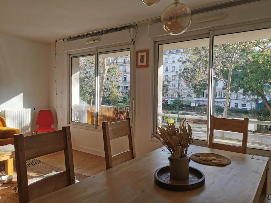 una sala da pranzo con tavolo e alcune finestre di Superbe appartement calme à République a Parigi