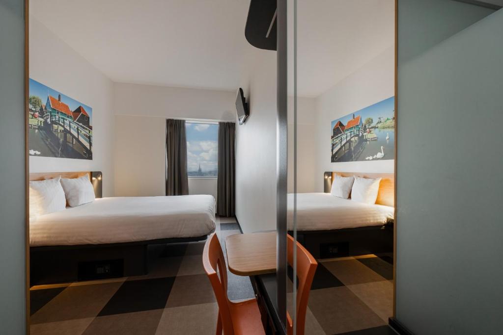 a hotel room with two beds and a table and a mirror at easyHotel Amsterdam Zaandam in Zaandam