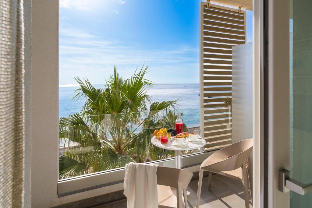 Albatros Beach Hotel في يتوجاني: طاولة وكراسي على شرفة مطلة على المحيط