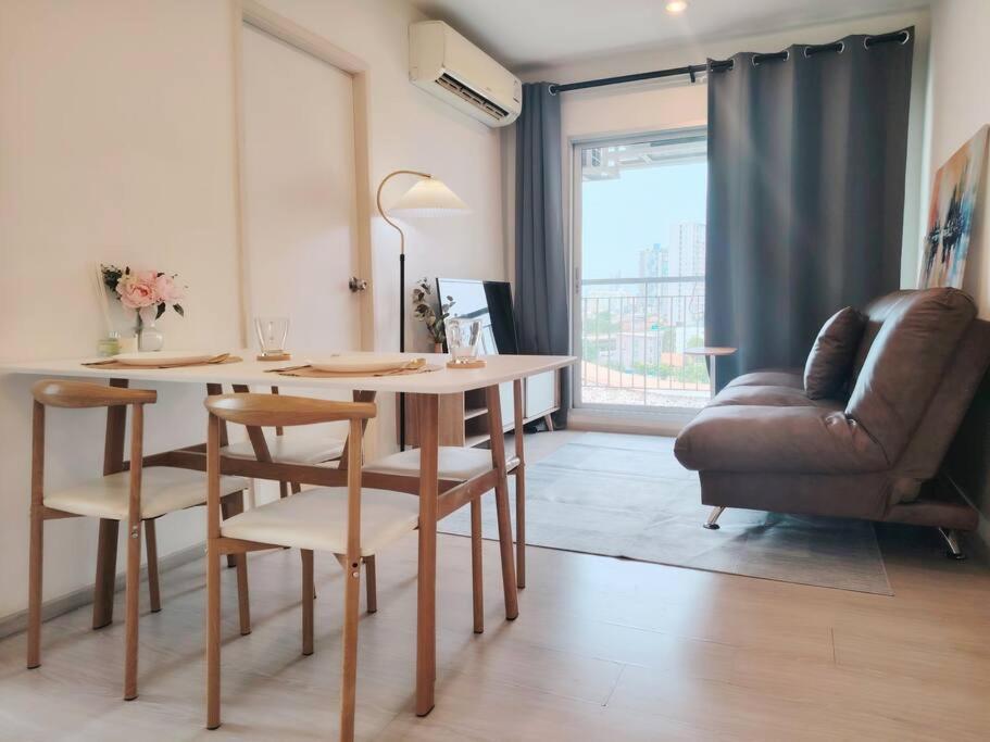 a living room with a table and a leather couch at 2BR, 6 Mins walk BTS Wuttakat in Bangkok