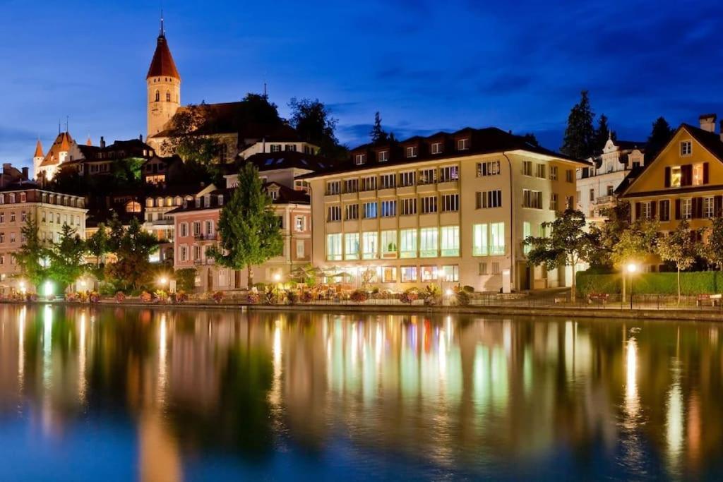 a city lit up at night with a body of water at House of Thun Full Apartment in Thun