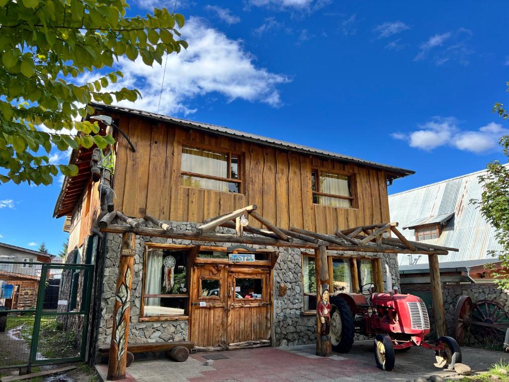 a wooden house with a red tractor in front of it at Ankatu Hostel in El Bolsón