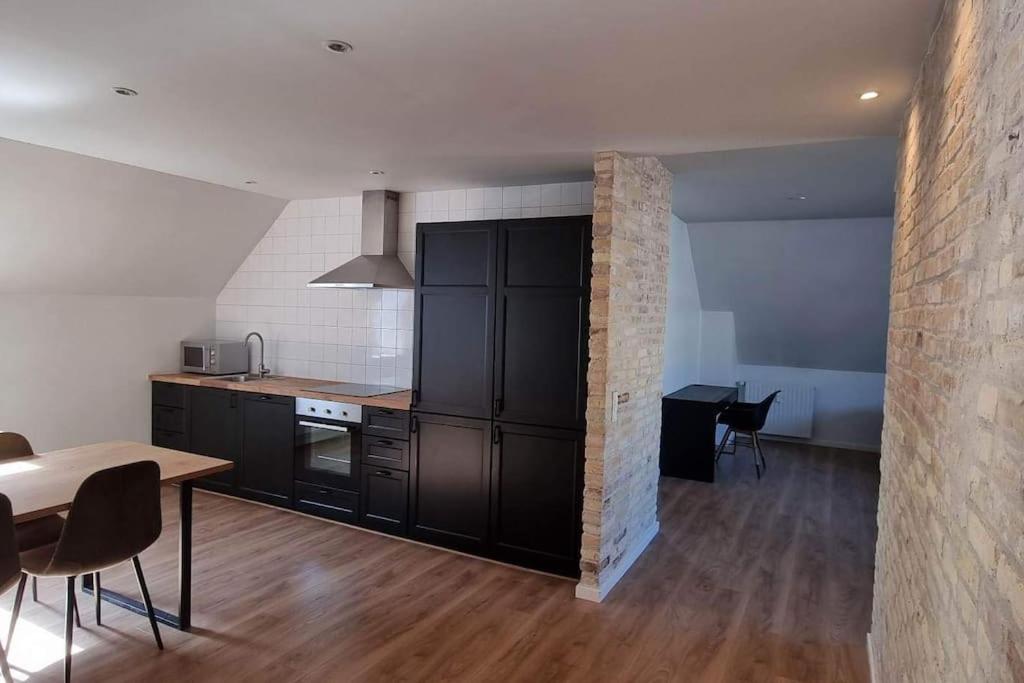 a kitchen with black cabinets and a table and chairs at Newly renovated, great location in Aalborg