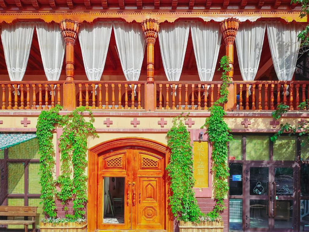 un edificio con puerta de madera y balcón con plantas en New Dap Hostel (in Grape Town), en Turfan