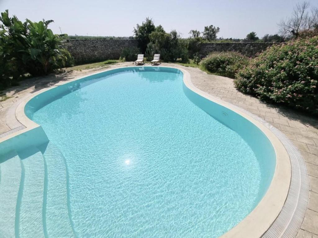 a large swimming pool with two chairs in it at Alghero Villa Rujia with garden and pool in Porto Conte