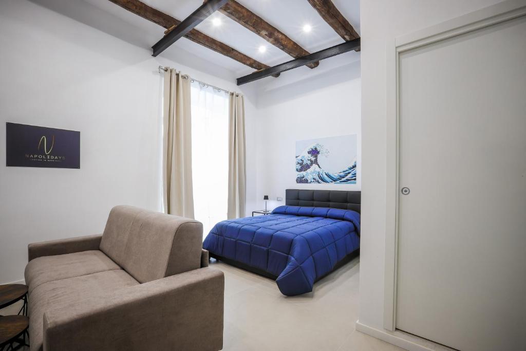 a bedroom with a bed and a couch and a chair at Napolidays Rua Catalana Apartment in Naples