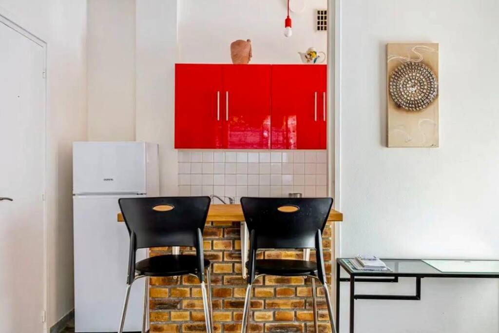 a kitchen with red cabinets and black stools at Charmant Appartement 4P Quartier Tour Eiffel in Paris