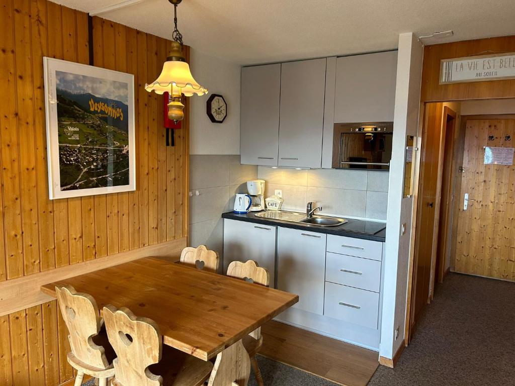 eine Küche mit einem Holztisch mit Stühlen und einem Waschbecken in der Unterkunft Hortensia MOUNTAIN & CENTER apartments in Veysonnaz