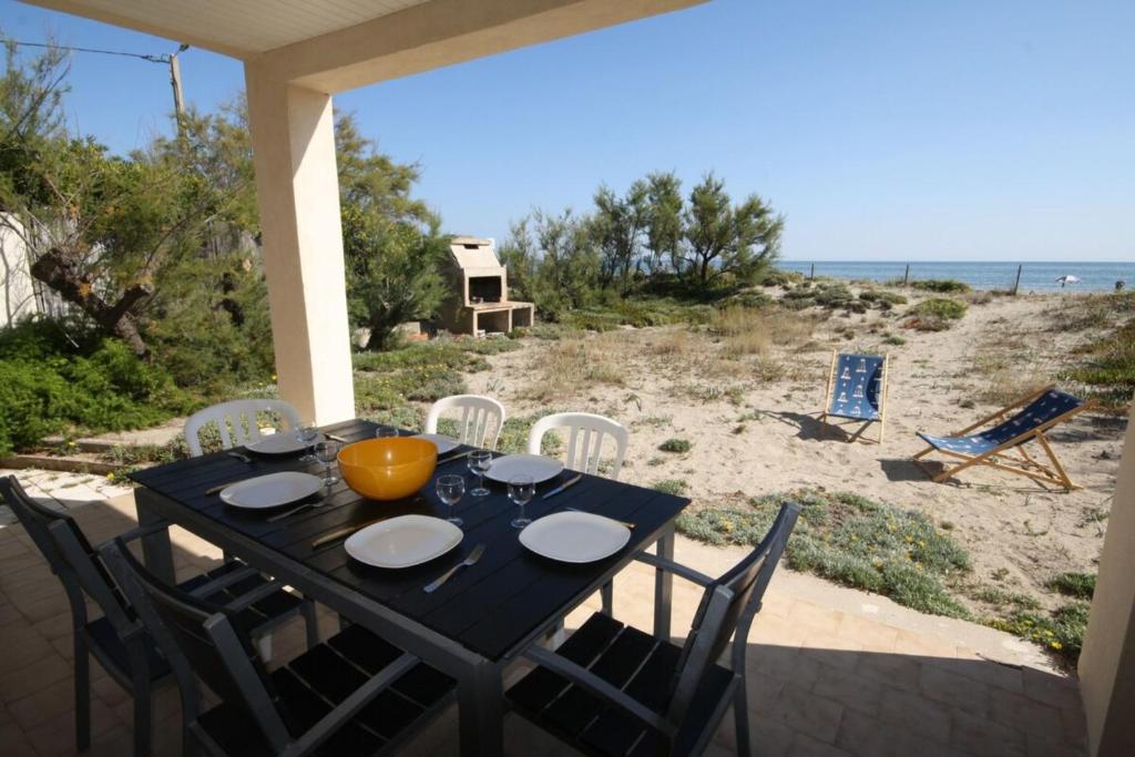 - une table noire avec des chaises et une vue sur la plage dans l'établissement Air-conditioned seafront house, à Frontignan
