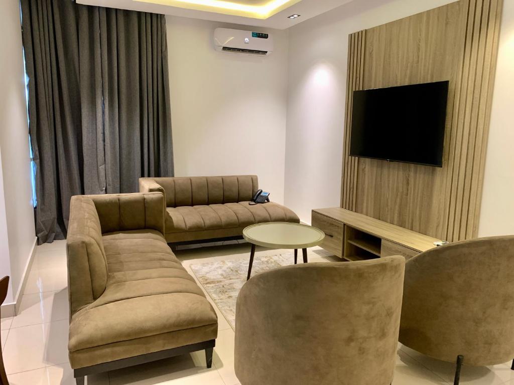 ein Wohnzimmer mit einem Sofa, Stühlen und einem TV in der Unterkunft Polo Grand Hotel in Maiduguri