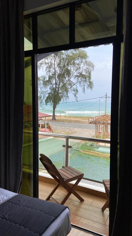 a room with a balcony with a chair and a view of the beach at Eleven25 Roomstay in Dungun
