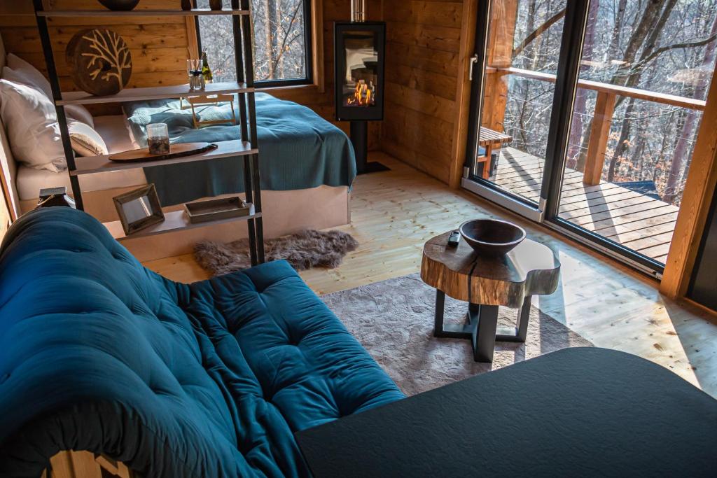 a living room with a blue couch and a bed at Chatka Nomád na Obrovisku in Muráň