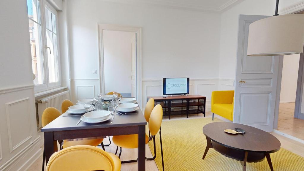 ein Esszimmer mit einem Tisch und gelben Stühlen in der Unterkunft Appartements Rue du Chêne in Mulhouse