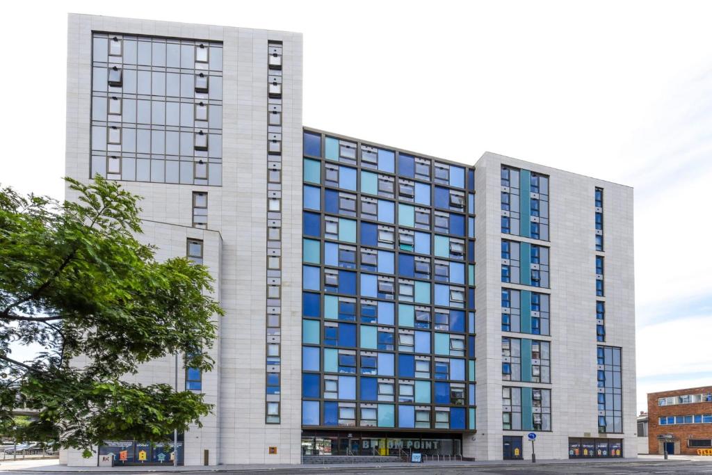 ein hohes weißes Gebäude mit blauen Fenstern in der Unterkunft Vibrant Byrom Point Retreat with Gym, Study Room and Social Lounge for Students Only in Liverpool