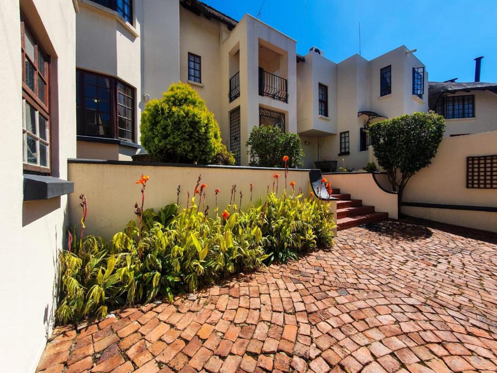 a brick driveway in front of a building with flowers at 2 Bedroom Self Catering Apartment in Waterkloofridge in Pretoria