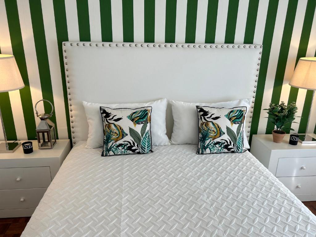 a bedroom with a white bed with four pillows at Casa "Patota" - Nazaré - Alojamento Local in Nazaré