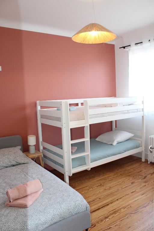 - une chambre avec des lits superposés blancs et un mur rose dans l'établissement Maison à 7 min à pied de la Côte des Basques (océan), à Biarritz