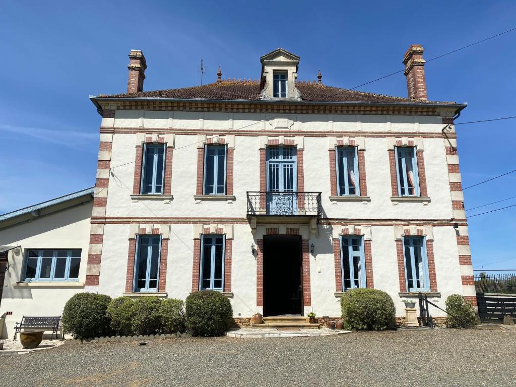 un grand bâtiment en briques avec une tour d'horloge en haut dans l'établissement A Gaillut, à Caupenne-dʼArmagnac
