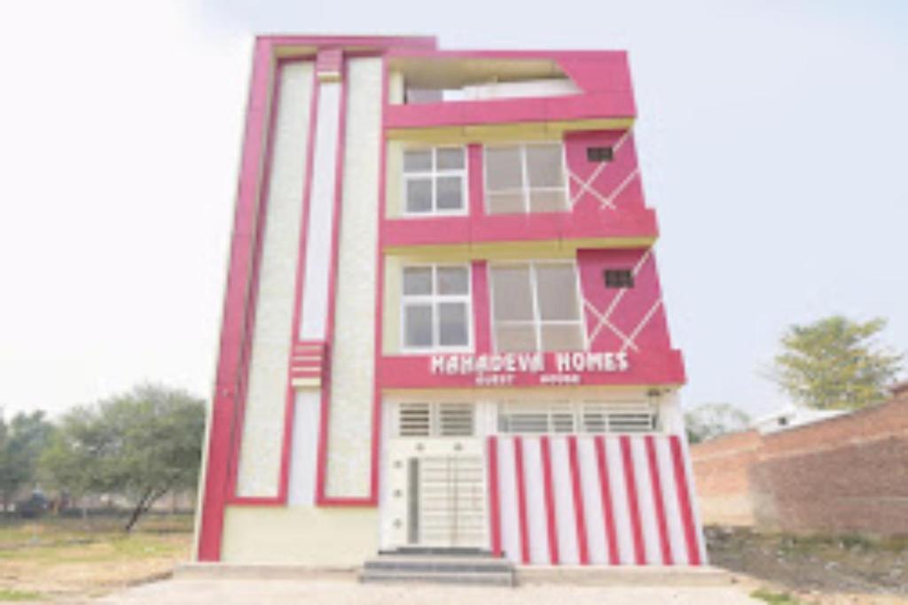 ein rot-weißes Gebäude mit einer Tür vorne in der Unterkunft GRG Mahadeva Homes Guest House Prayagraj in Prayagraj