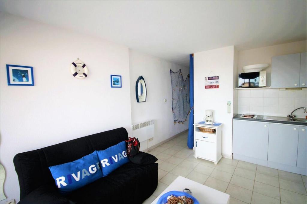 uma sala de estar com um sofá preto e uma cozinha em The sea within sight em Frontignan