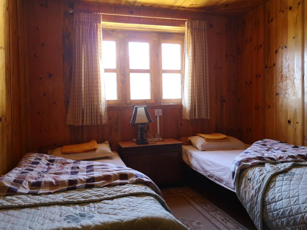 LuklaにあるLukla Himalaya Lodgeのウッドルーム ベッド2台 窓付