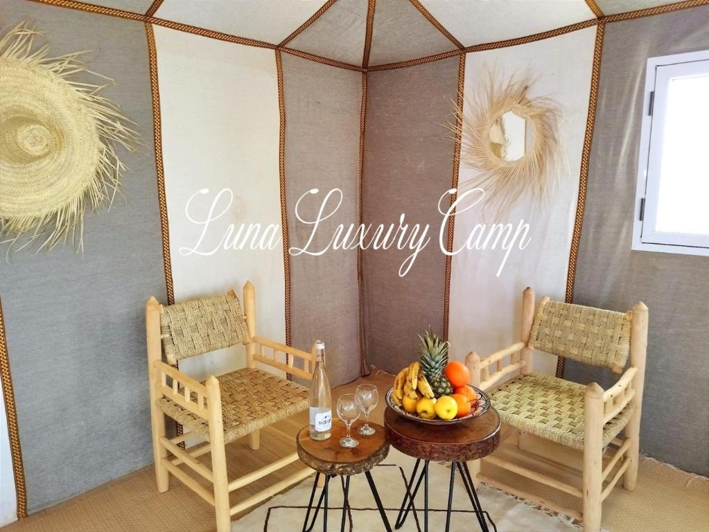a room with two chairs and a table with a bowl of fruit at Luna luxury camp in Merzouga
