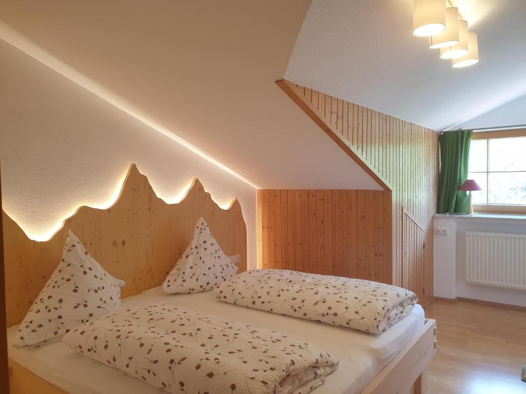 a bedroom with a large bed with a wooden headboard at AlpenFerienLandhaus Müller in Rettenberg