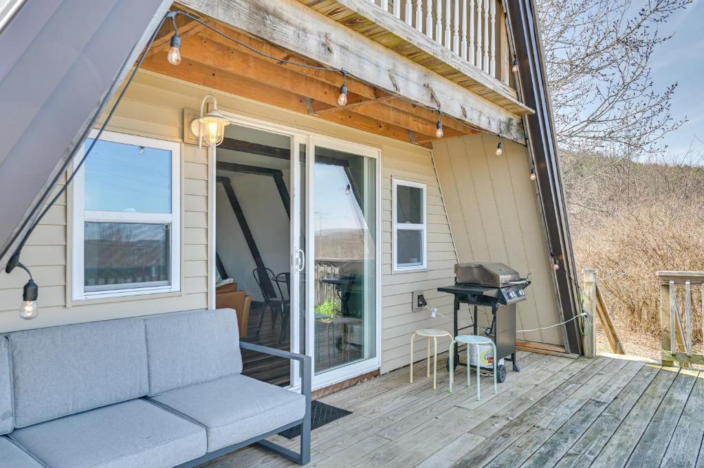 eine Veranda mit Sofa und Grill auf einem Haus in der Unterkunft A-Frame Catskills Cabin with Scenic Views and Hot Tub! in Stamford