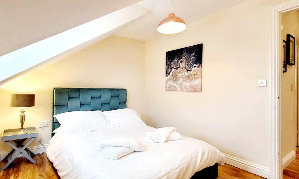 1 dormitorio con 1 cama con cabecero azul en Apartment 5 - two bedroom luxury apartment close to town, mainline rail & theatre stylish and comfortable, en Darlington