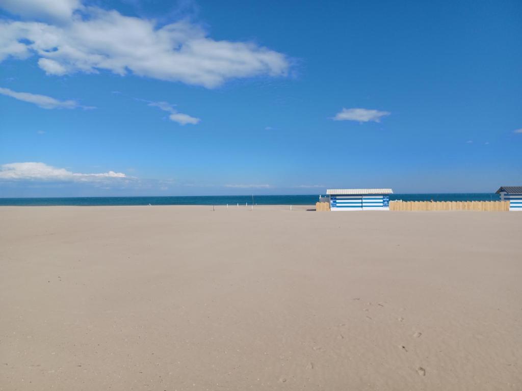 einen Sandstrand mit blauem Himmel und Wolken in der Unterkunft Mobil-Home pour 6 personnes (3 chambres) in Narbonne