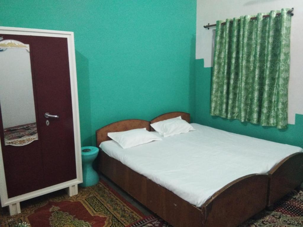 Habitación pequeña con cama y pared verde en Gyanbhumi Homestay Ayodhya, en Faizābād