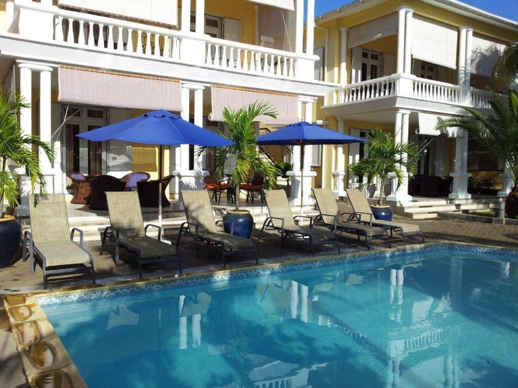 a swimming pool with chairs and umbrellas next to a building at Résidence Syrina 1 in Trou aux Biches