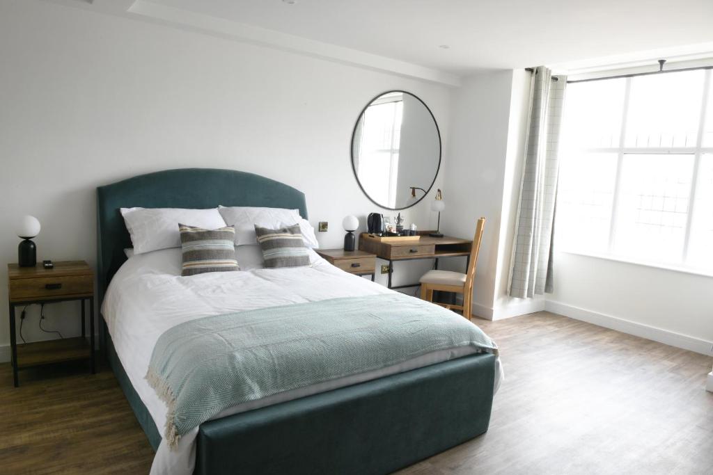 een slaapkamer met een bed met een spiegel en een bureau bij The Almshouse Suites in Woburn Sands
