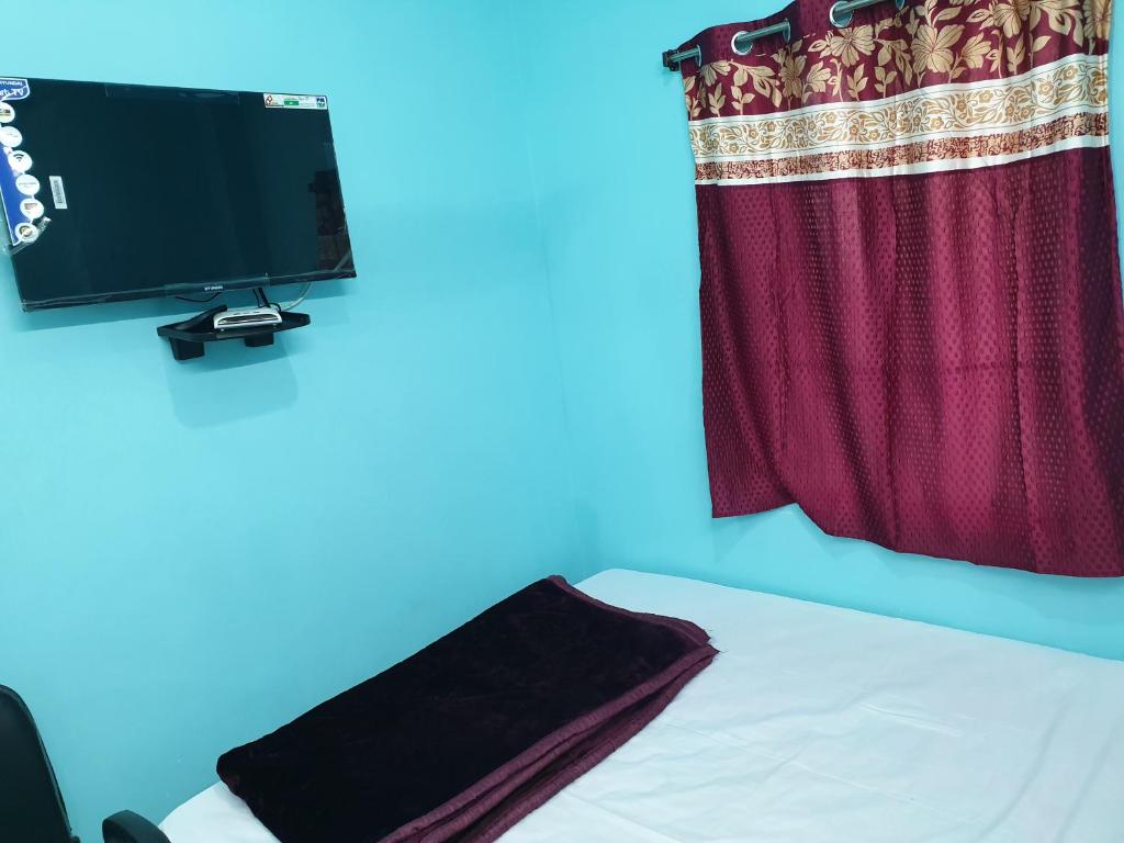 a bedroom with a bed and a television on a wall at Hotel Ambika in Deoghar