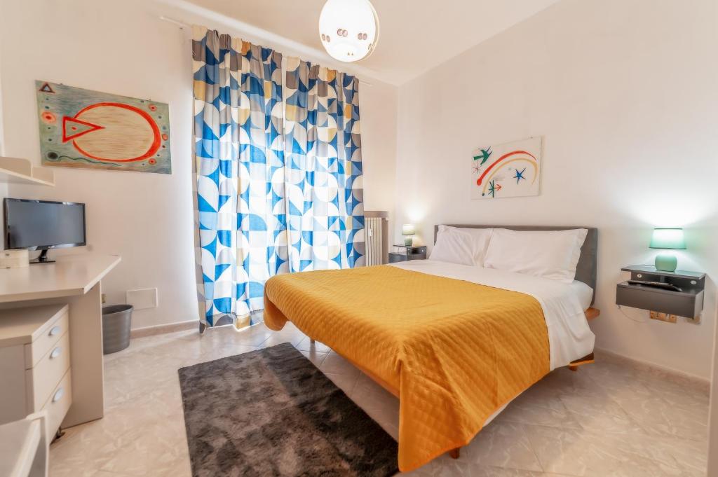 a bedroom with a bed with a yellow blanket and a tv at Luisa Flat - Metro Basilica San Paolo in Rome