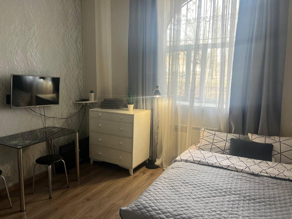 ein Schlafzimmer mit einem Bett, einer Kommode und einem Fenster in der Unterkunft Smart in Kharkov