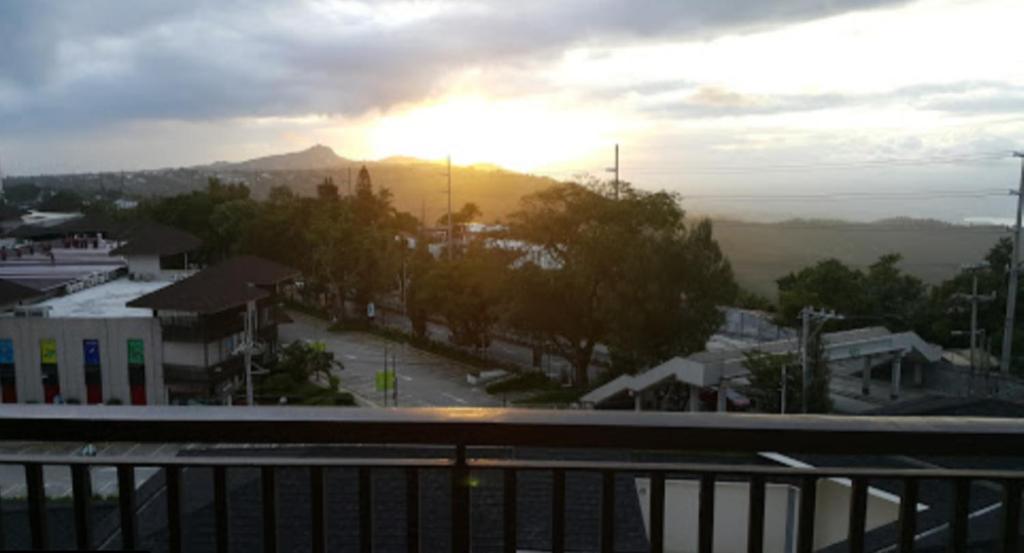 einen Blick vom Balkon einer Stadt mit Sonnenuntergang in der Unterkunft Casa de Guapo - AYALA Serin East Taal View Condo in Tagaytay