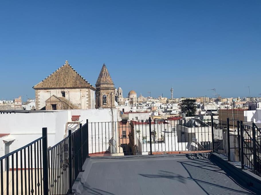 einen Blick auf eine Stadt von einer Dachterrasse mit einem Zaun in der Unterkunft El Ático de los Girondinos in Cádiz