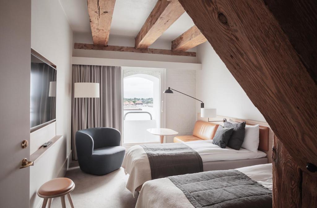 a bedroom with a bed and a couch and a chair at Copenhagen Admiral Hotel in Copenhagen